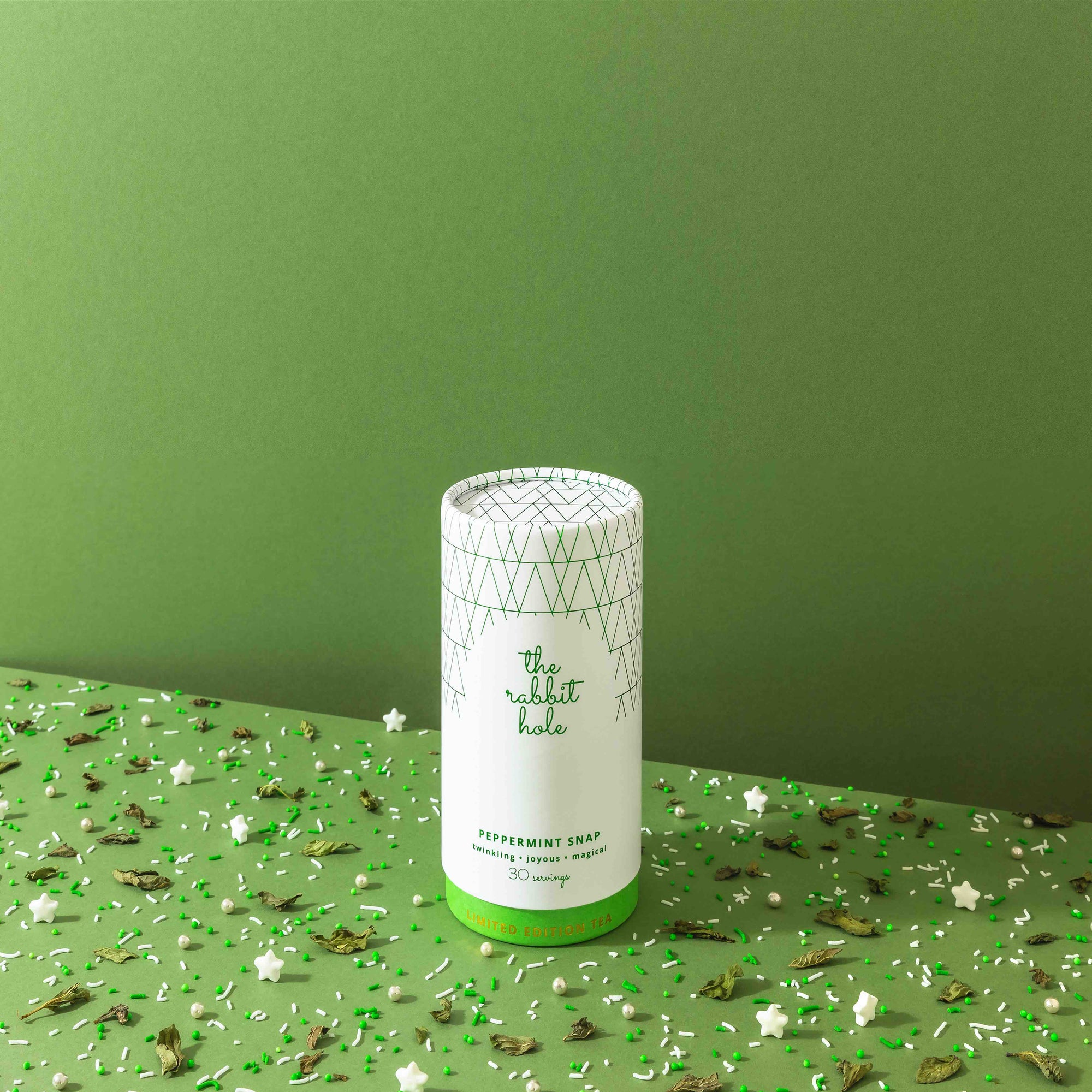 Peppermint Snap Christmas Tea with sparkles by The Rabbit Hole - canister on a bright green background with sprinkles.